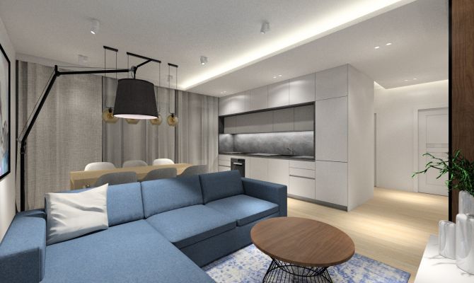 Aranżacja aneksu kuchennego - białe meble połączone z szarym blatem. Narożnik w salonie, niebieski dywan i lampa do czytania.